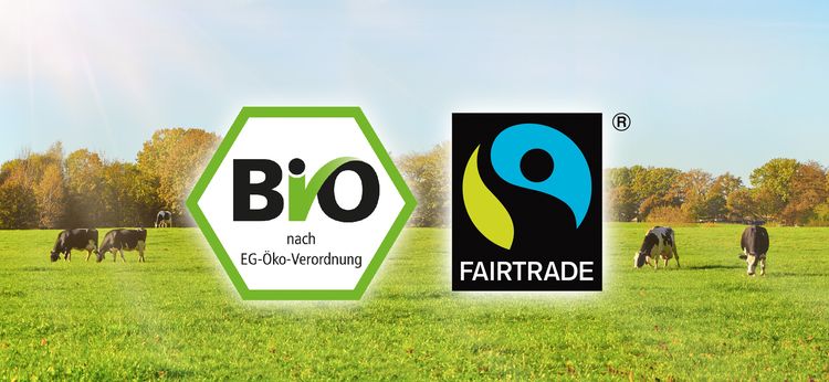 Kühe auf einer Wiese, in der Mitte des Bildes Bio- und Fairtrade-Siegel