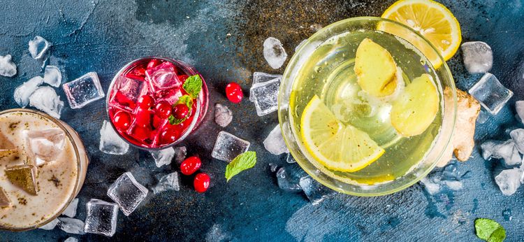 Drei Getränke mit Eiswürfeln und unterschiedlichen Früchten, von oben fotografiert
